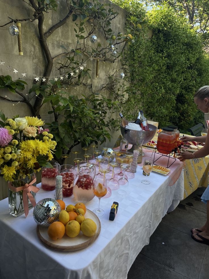 Mesa de verano con limonada, flores y frutas en un jardín
